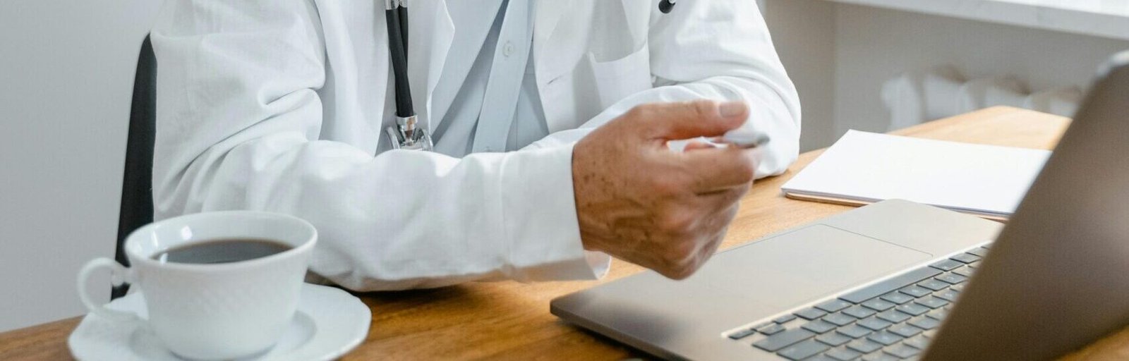Elderly doctor using laptop for a virtual consultation in a modern office.